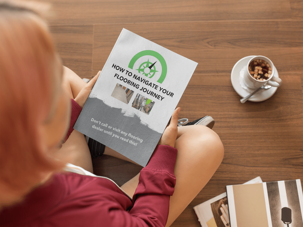 a girl holding a book while sitting down on a wooden floor