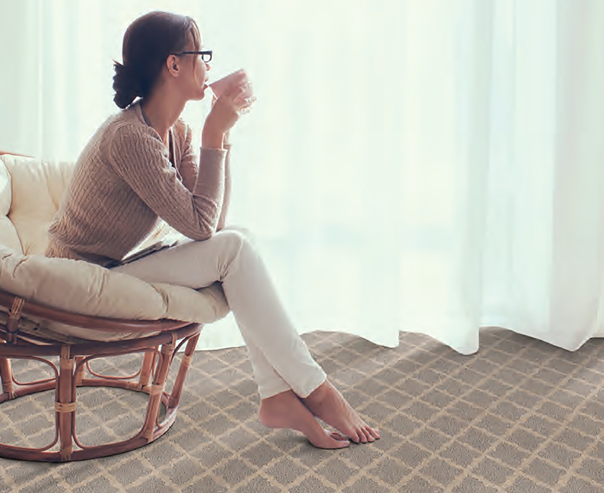 lady drinking coffee in a chair on living room carpet