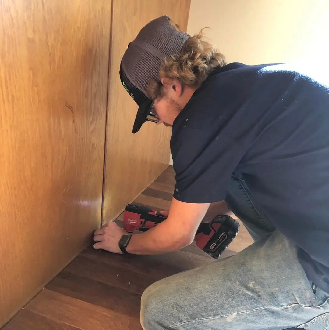 installer trimming cabinets to prepare for new wall base